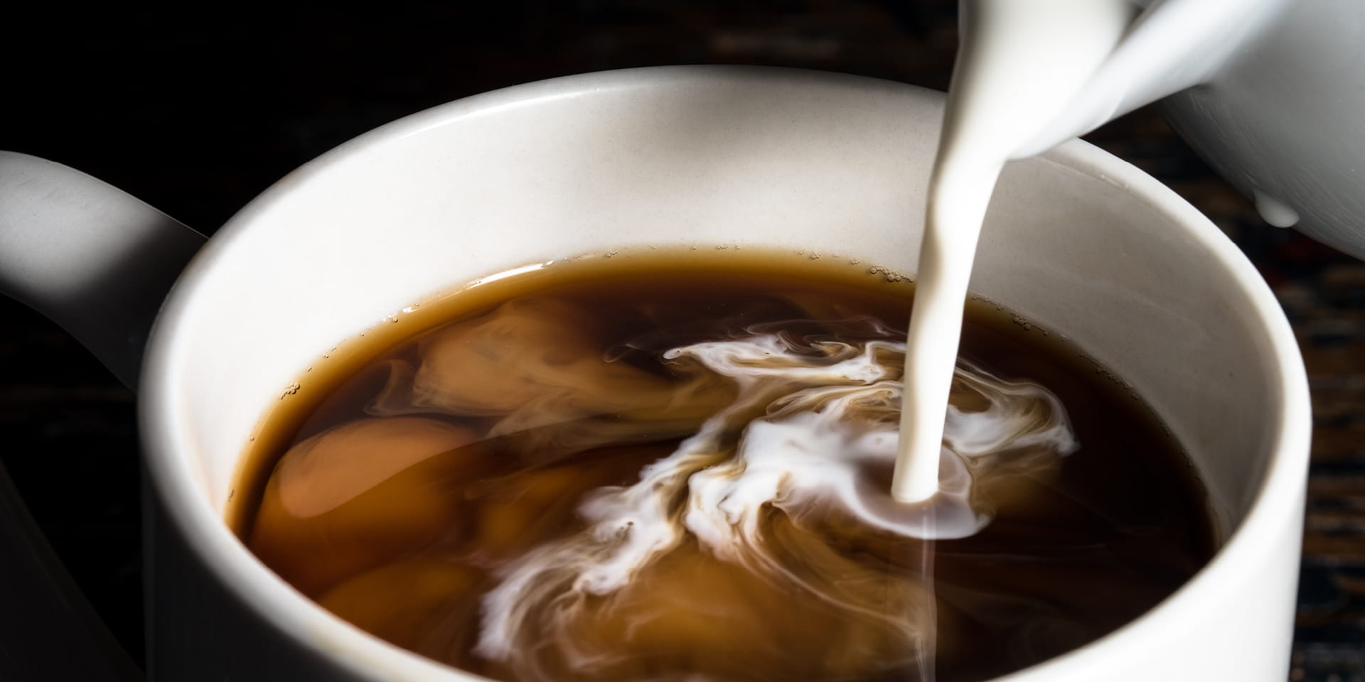 Cream being poured into a coffee cup