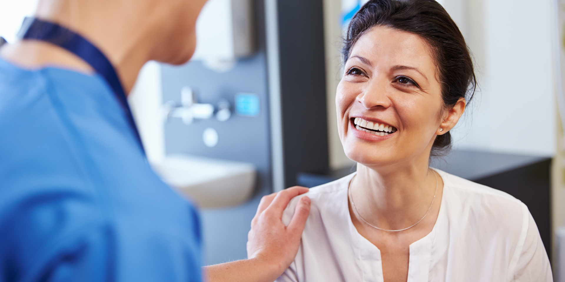 Doctor with hand on smiling female patient's shoulder