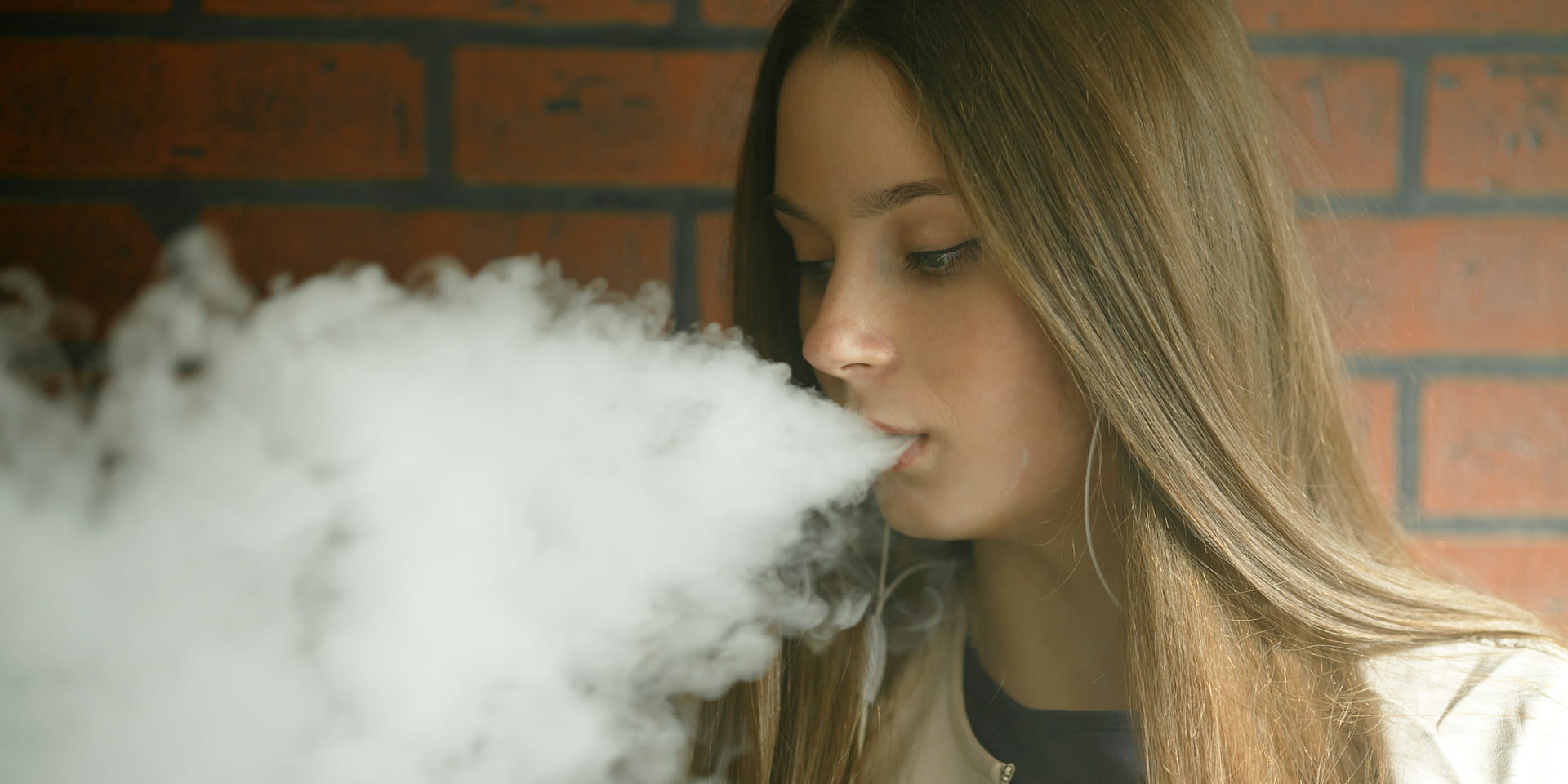 teenage girl blowing out smoke