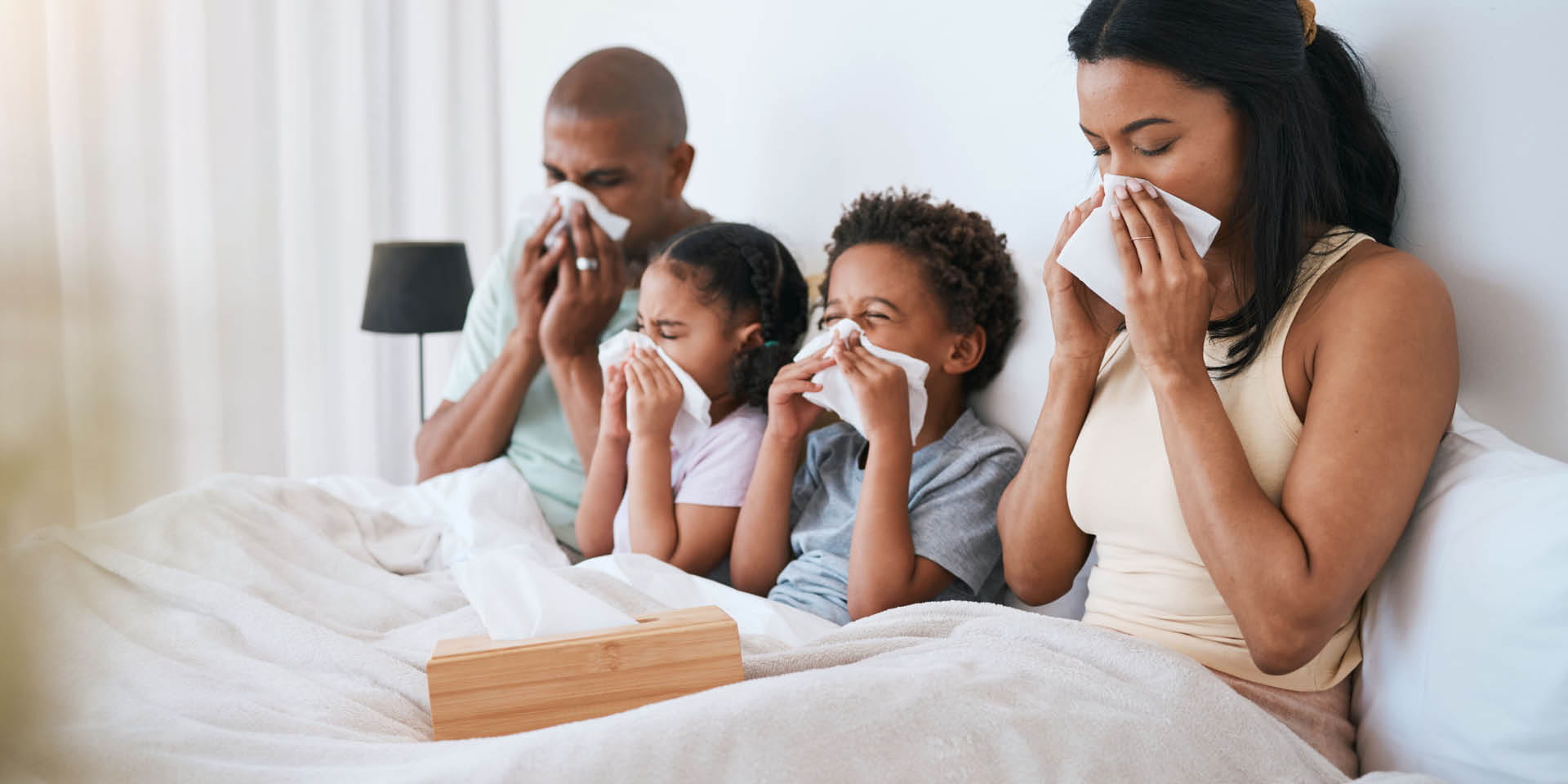 Family in bed blowing their nose | Doylestown Health