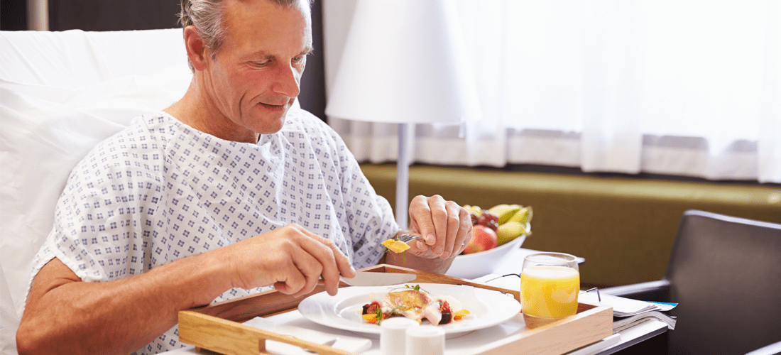 Male Patient In Hospital Bed Eating Meal From Tray | Doylestown Health