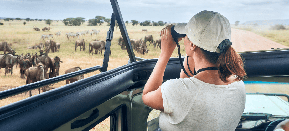 Woman looking at wild animals through binoculars | Doylestown Health